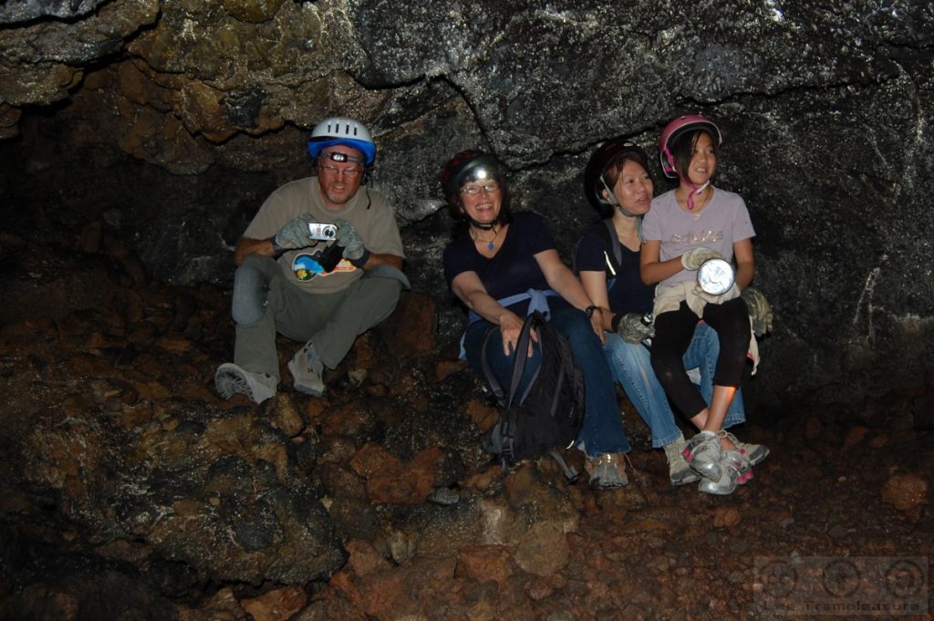Photo showing four people in a cave with helmets. One is a girl.